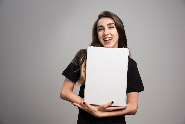 Young woman with happy expression holding canvas. 