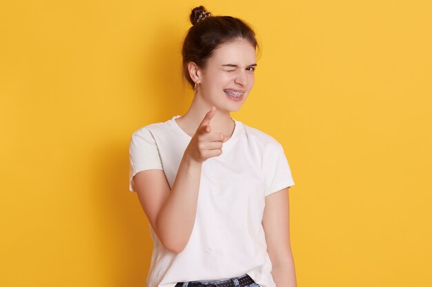 黄色の壁に分離されたポーズ幸せな表情を持つ若い女