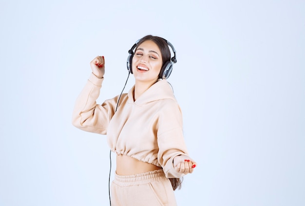 Young woman with headphones listening to the music and dancing