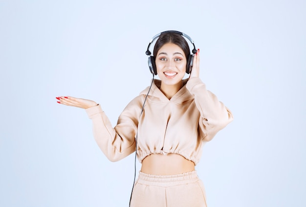 Young woman with headphones pointing or noticing someone on the left