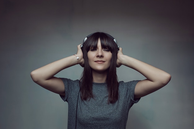 Free photo young woman with headphones on wall