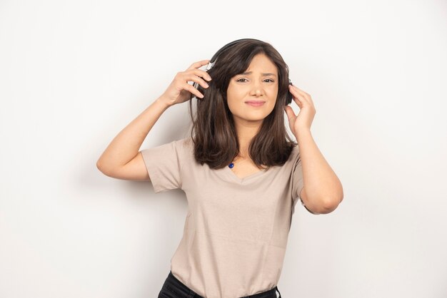 Young woman with headphones on white background.