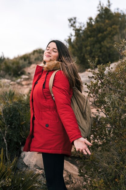 Young woman with her backpack enjoying fresh air in the mountain