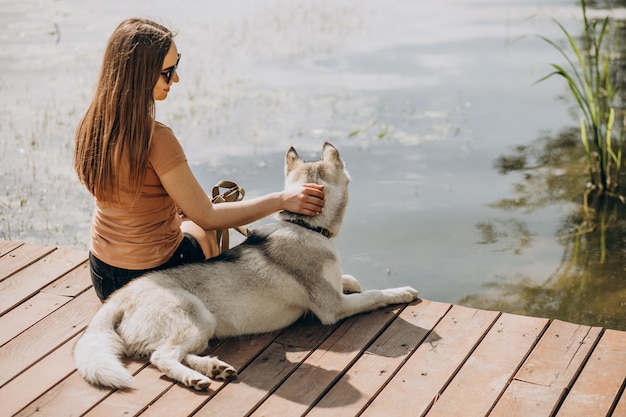 湖のほとりに彼女のハスキー犬を持つ若い女性