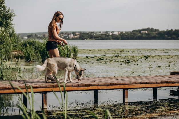 湖のほとりに彼女のハスキー犬を持つ若い女性