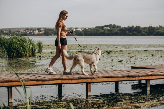 湖のほとりに彼女のハスキー犬を持つ若い女性