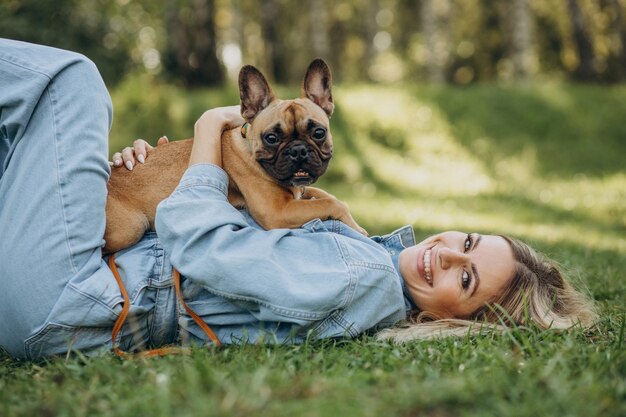 Free photo young woman with her pet french bulldog in park