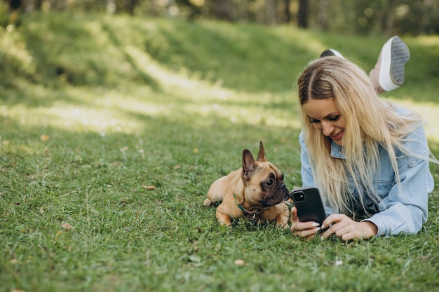 Young woman with her pet french bulldog in park