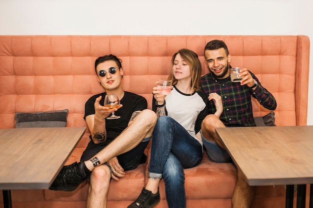 Молодая женщина с двумя мужскими друзьями, пить напитки в ресторане