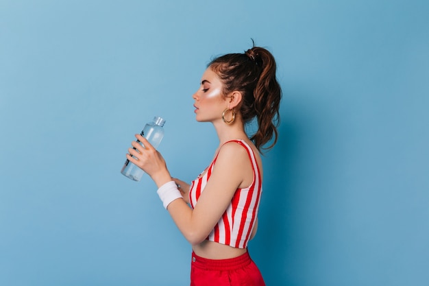 Free photo young woman with highlighter on face drinks water