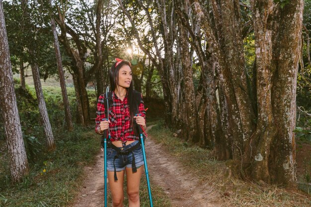Young woman with hiking pole exploring forest