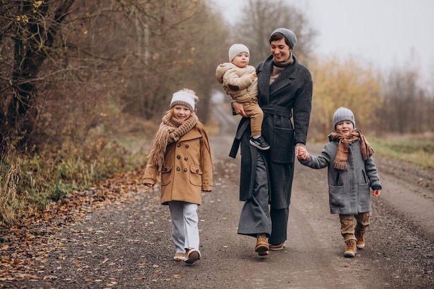 Young woman with kids walking in autumn park