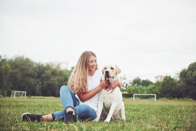 young woman with labrador outdoors. Woman on a green grass with dog labrador retriever.