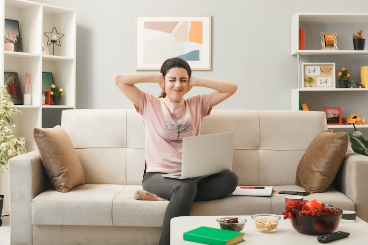 無料Photo リビングルームのコーヒーテーブルの後ろのソファに座っているラップトップを持つ若い女性