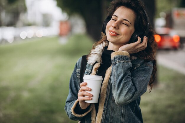 Young woman with listening music and drinking coffee