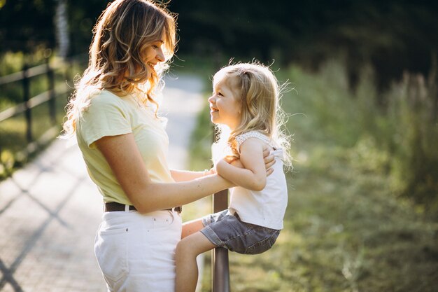 Young woman with little daughter walking in park