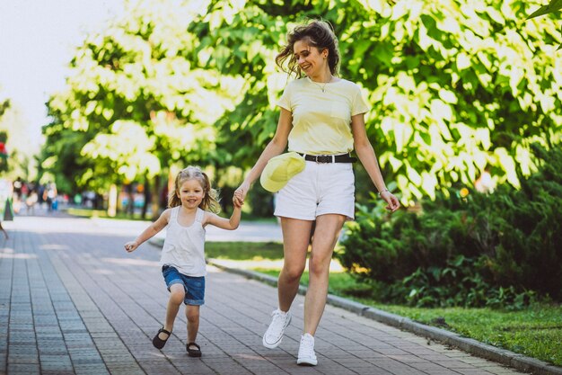 公園を歩いて小さな娘を持つ若い女性