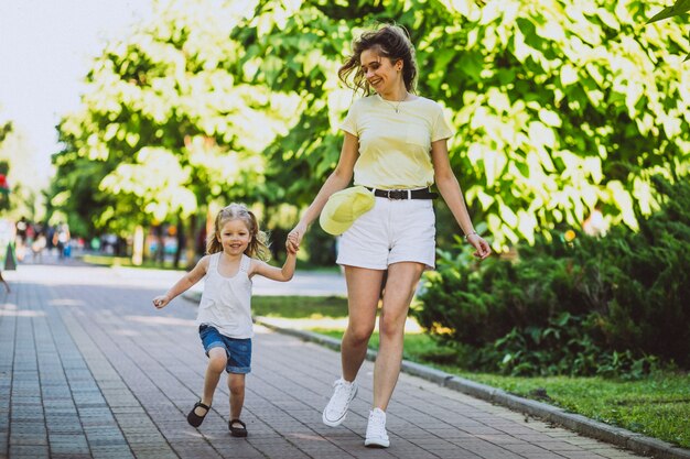Young woman with little daughter walking in park