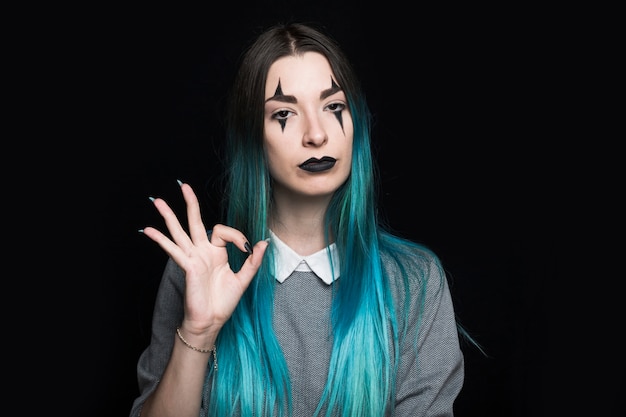 Young woman with long blue hair showing ok gesture