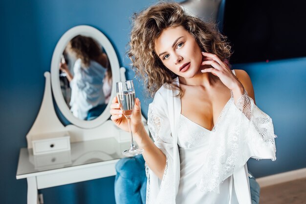 Young woman with a long curly hair celebrating married with champagne