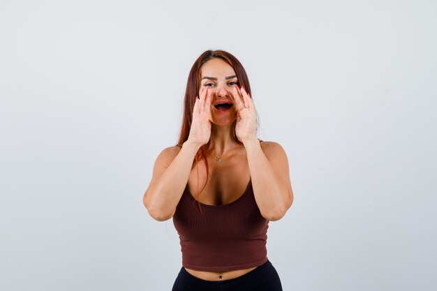 Young woman with long hair in a brown crop top shouting