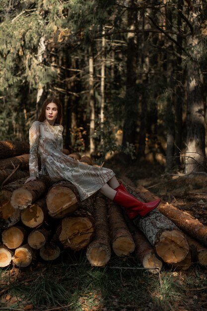 森の中でキノコを集めるリネンドレスの長い赤い髪の若い女性