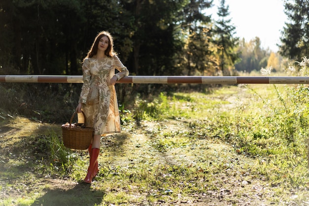 Young woman with long red hair in a linen dress gathering mushrooms in the forest 