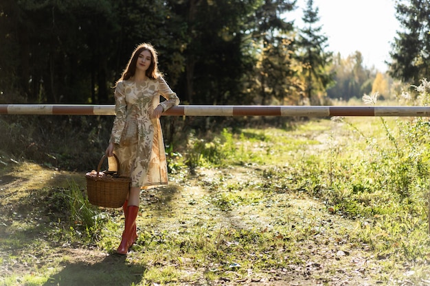 Молодая женщина с длинными рыжими волосами в льняном платье, собирающих грибы в лесу