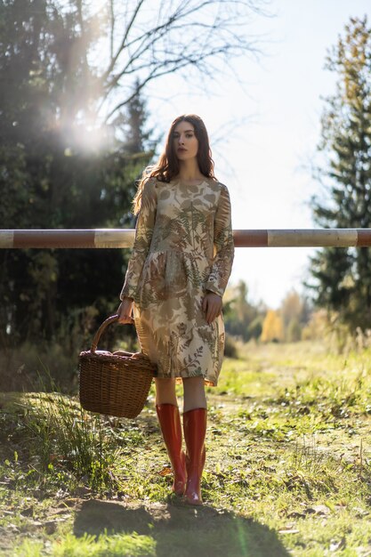 Young woman with long red hair in a linen dress gathering mushrooms in the forest 