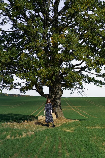 Young woman with long red hair in a linen dress in a natural location 