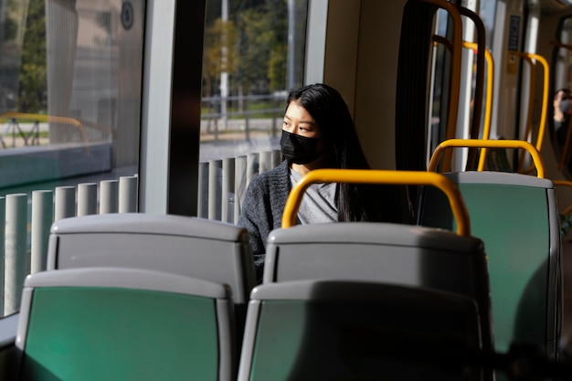 Giovane donna con la maschera in autobus