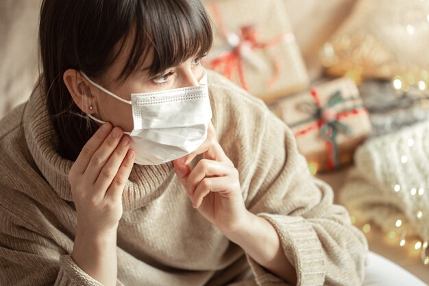 Young woman with mask on her face in a cozy beige sweater  