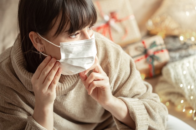 아늑한 베이지 색 스웨터에 그녀의 얼굴에 마스크와 젊은 여자