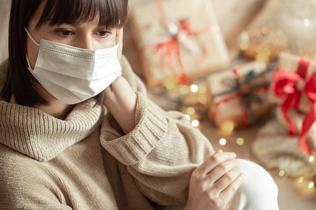 Foto gratuita giovane donna con la maschera sul viso in un accogliente maglione beige