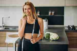 Free photo young woman with measuting tape at the kitchen