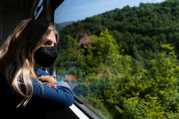 무료 사진 아름다운 자연 경관을 바라보는 의료용 마스크를 쓴 젊은 여성