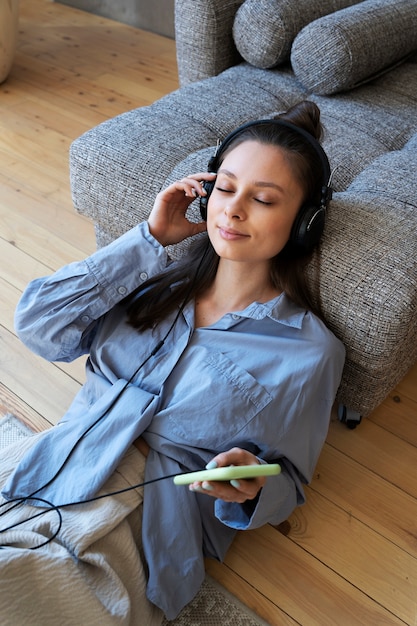 Бесплатное фото Молодая женщина с грязной булочкой слушает музыку