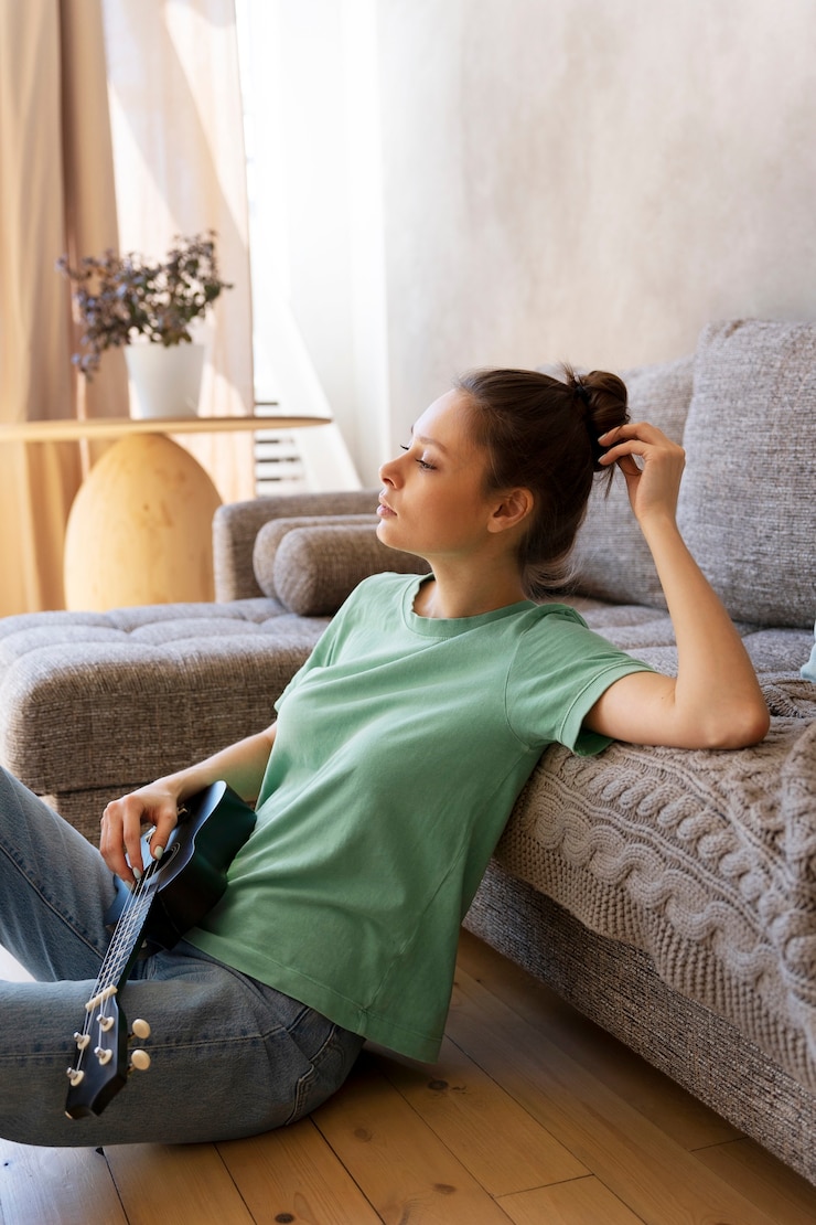 Free Photo young woman with messy bun playing ukulele