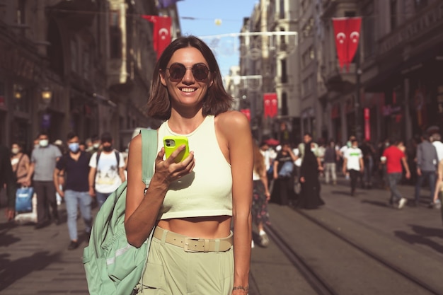 Young woman with mobile phone travels through the crowded streets of istanbul happy enjoying the beauty of the city