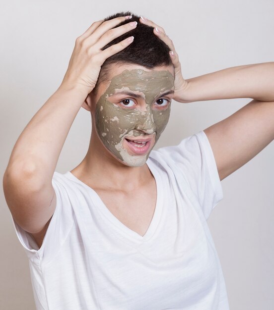 Young woman with mud treatment looking at camera 