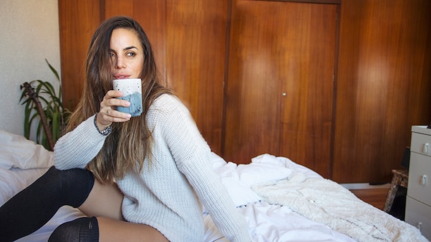 Free photo young woman with mug on bed