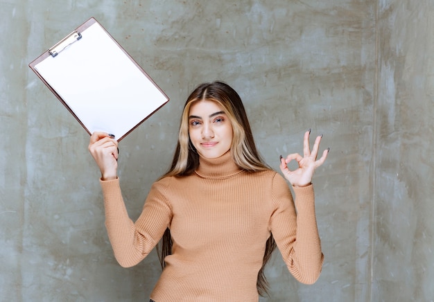 Young woman with notepad showing ok gesture on a stone 