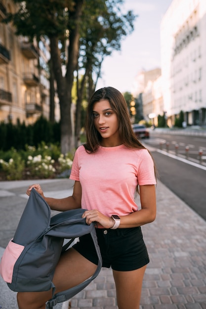 Young woman with open backpack on the street. Portrait of a young woman