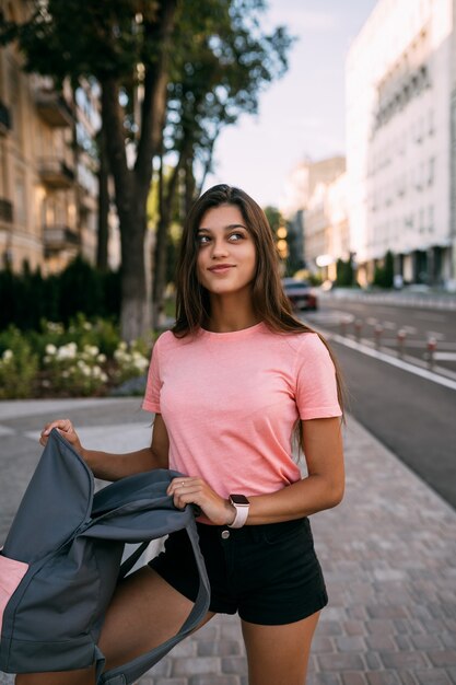 Young woman with open backpack on the street. Portrait of a young woman