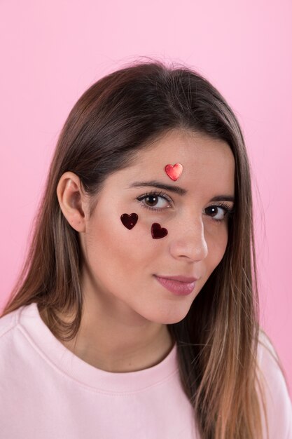 Young woman with ornament hearts on face 