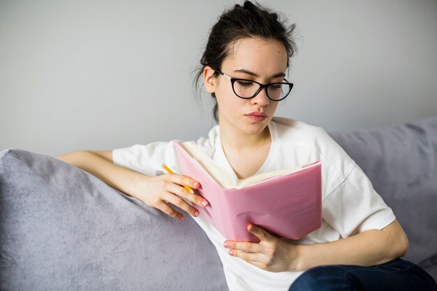 Young woman with pencil reading book