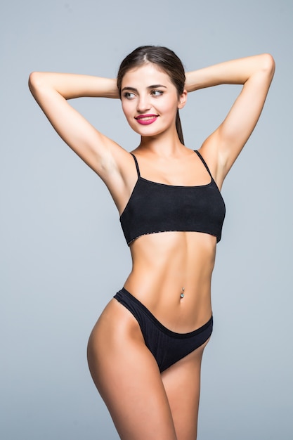 Young woman with perfect body wear in black underwear on white wall