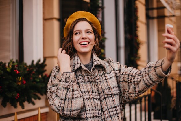 Young woman with perfect skin is smiling while taking selfie