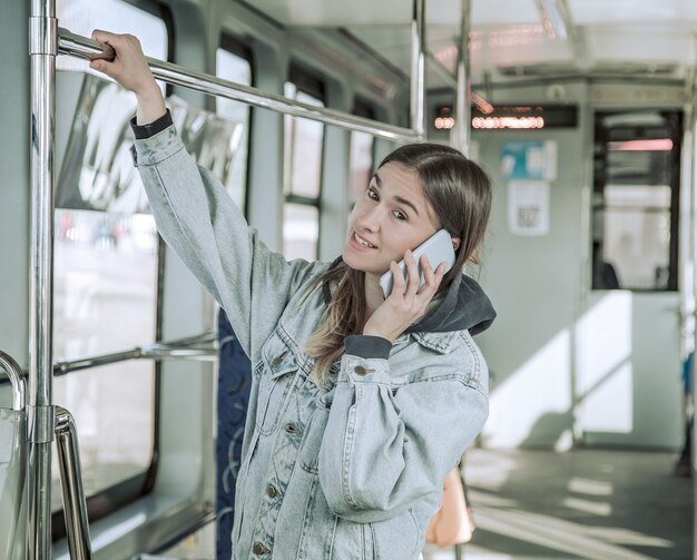 公共交通機関で電話を持つ若い女性。