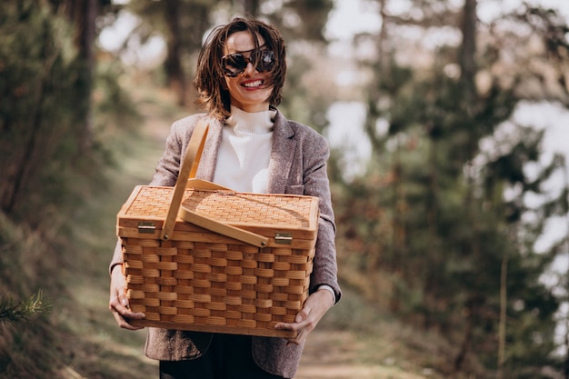 Free photo young woman with picnic box in the forest